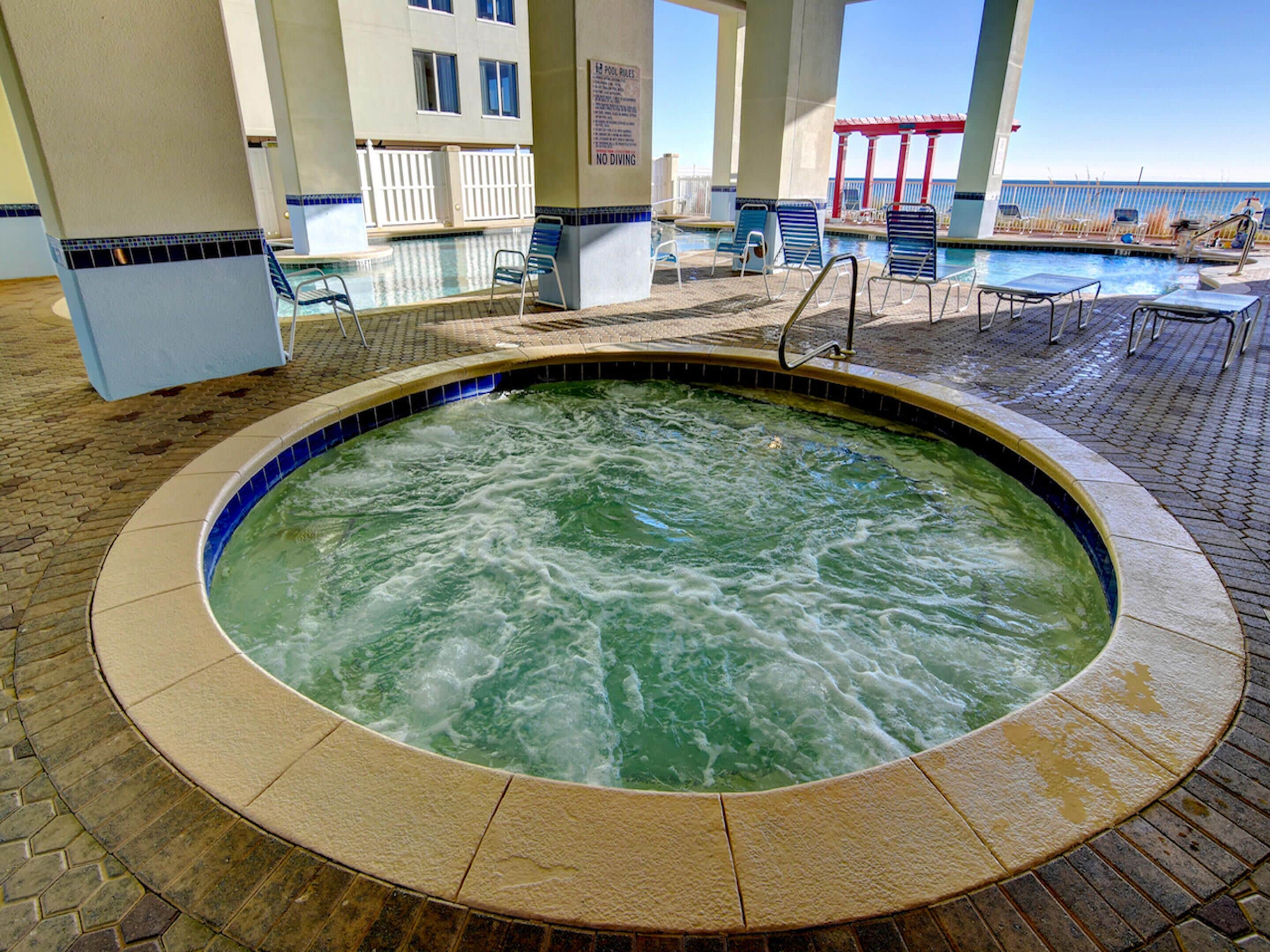 A hot tub surrounded by lounge chairs and a pool area.