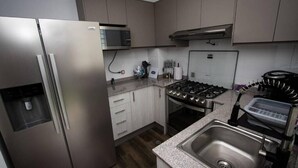 Moderni keittiö, jossa on ruostumattomasta teräksestä valmistetut kodinkoneet, sisäänrakennettu mikroaaltouuni, kaasuliesi ja graniittitaso.