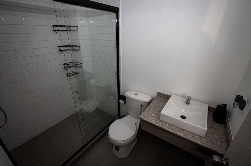 Une salle de bain avec une douche à parois de verre, des toilettes et un lavabo avec un plan de travail.