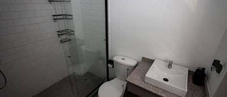 Une salle de bain avec une douche à parois de verre, des toilettes et un lavabo avec un plan de travail.