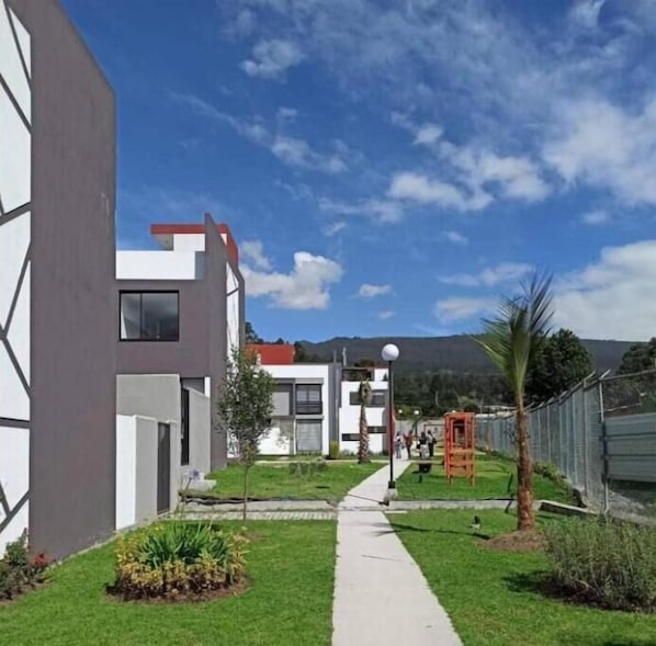 Un edificio moderno con un sendero que lleva a una entrada protegida por una reja.
