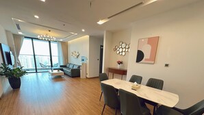 Ein modernes Wohnzimmer mit Essbereich, einer Couch, einem Couchtisch und einem großen Fenster mit Vorhängen.