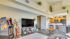 A spacious living room with a large flat-screen TV, arcade games, and a cozy seating area.