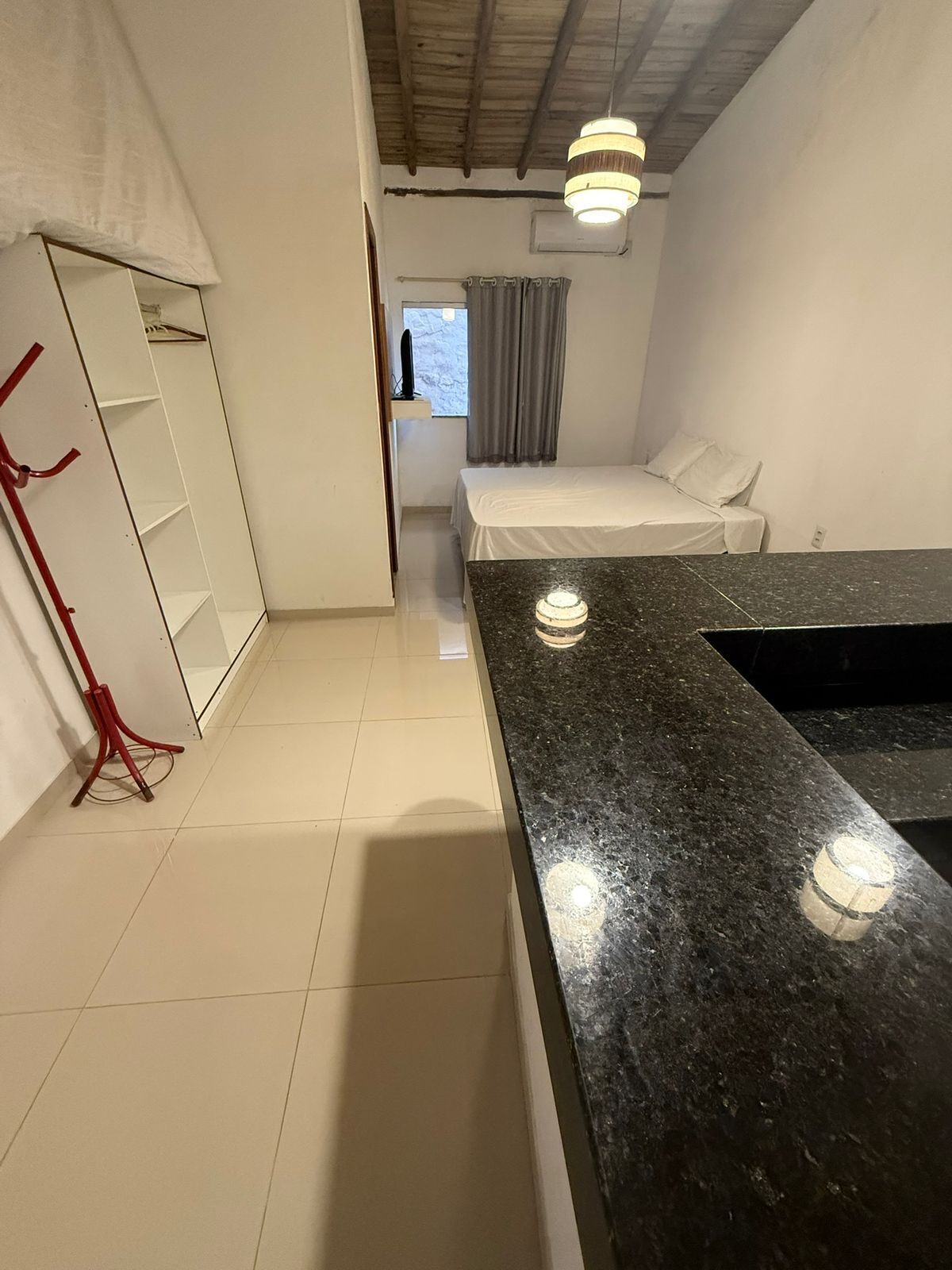Una habitación con cama, armario, escritorio y ventana con cortinas.