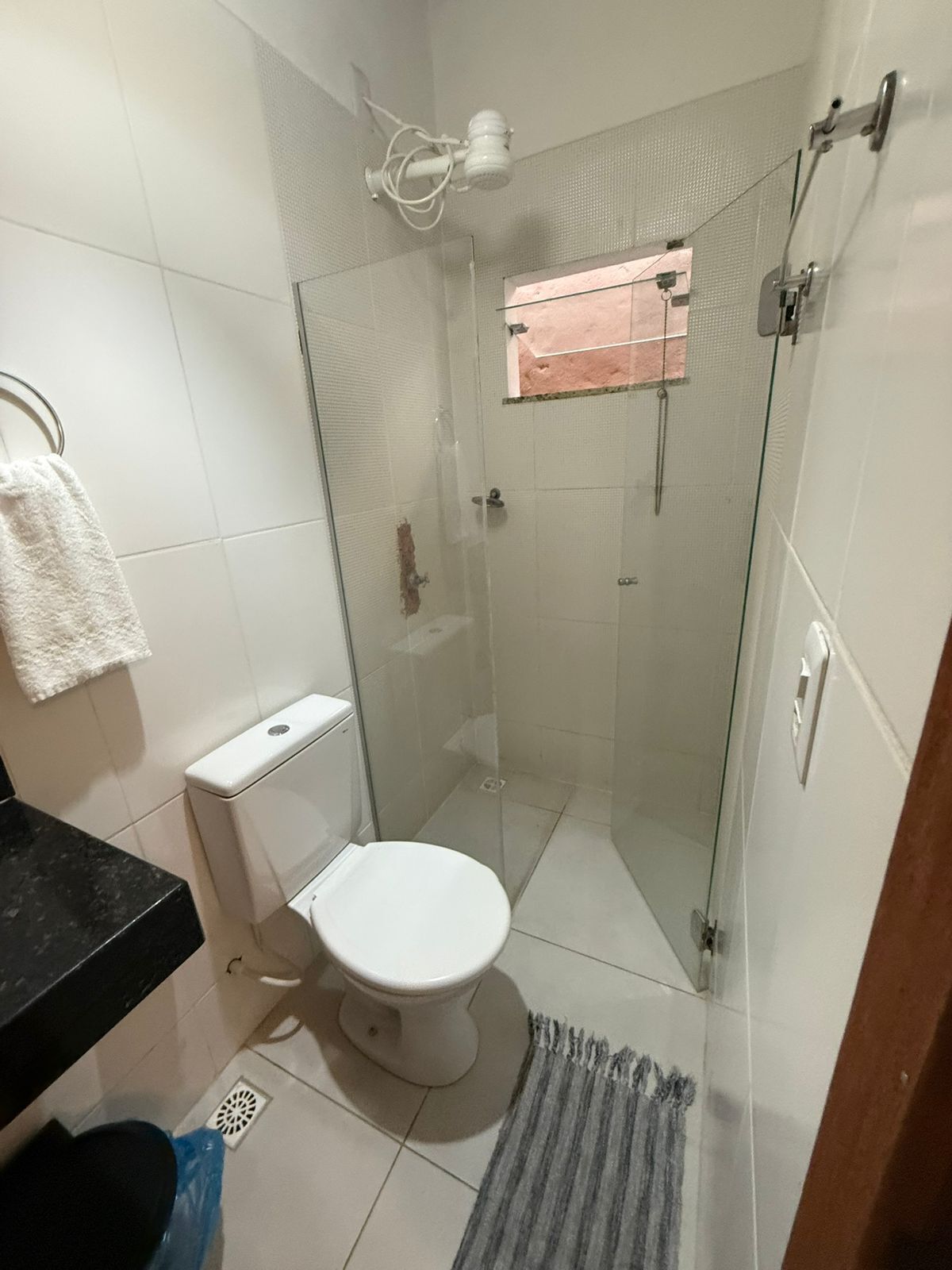 A small bathroom with a toilet, a shower, and a towel rack.