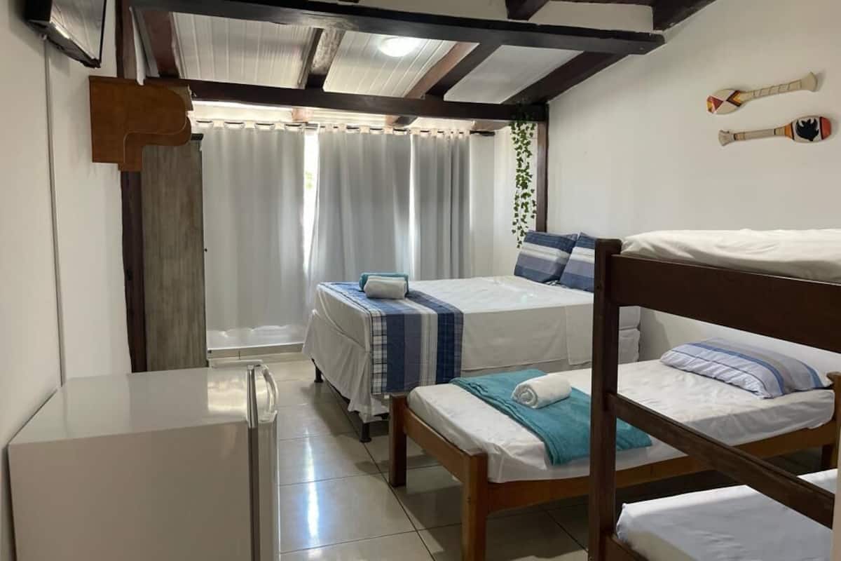 A bedroom with two beds, a wooden headboard, a small table, and a window with curtains.