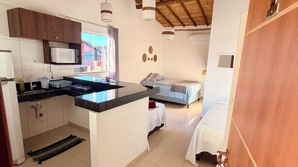 A compact kitchen with a microwave, sink, and wooden ceiling. - Pousada Portal do Mucugê (Porto Seguro)