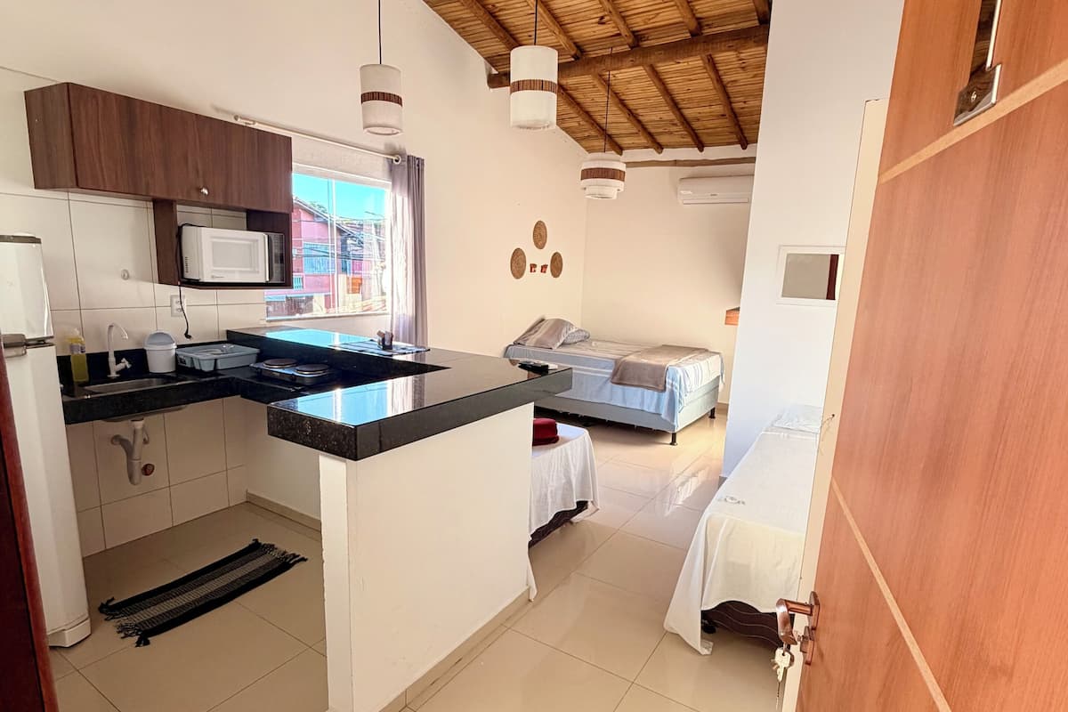 A compact kitchen with a microwave, sink, and wooden ceiling.