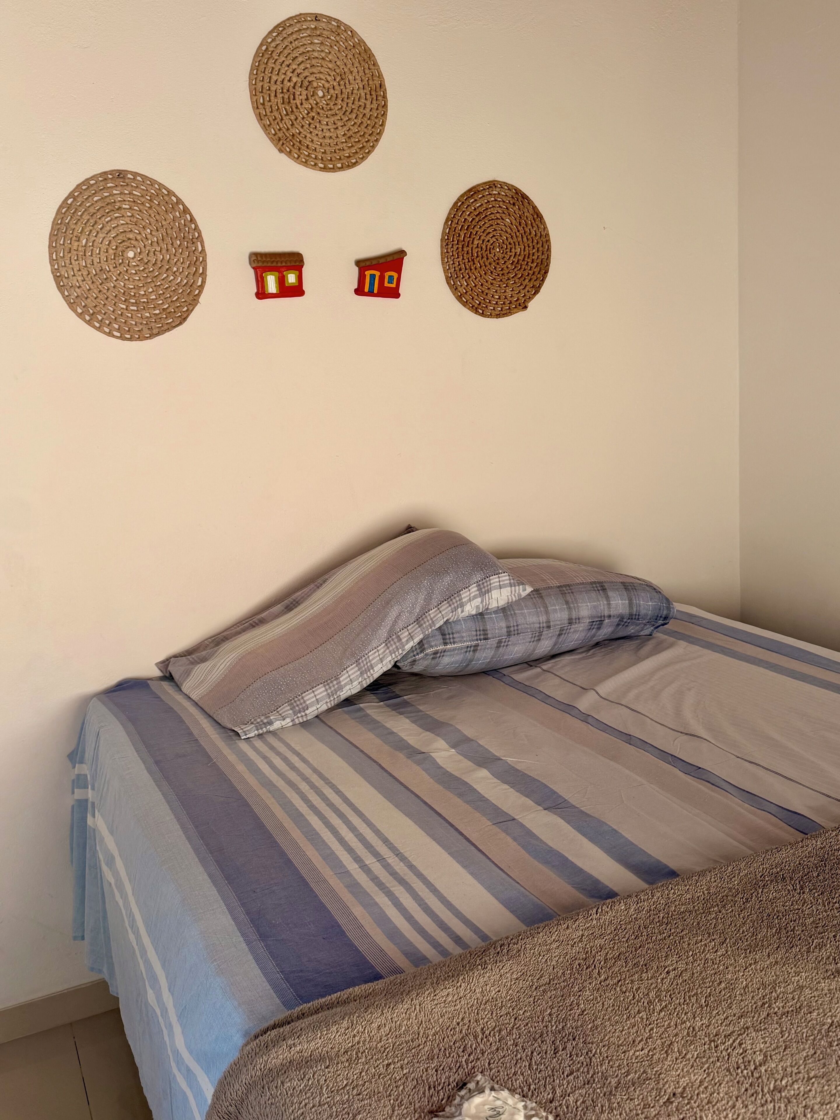 Uma cama com roupa de cama listrada, um travesseiro xadrez e um cobertor marrom.