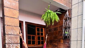 A stone building with a hammock, potted plants, and a hanging plant. - Pousada Portal do Mucugê (Porto Seguro)
