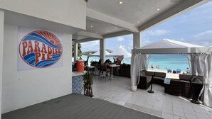 A covered outdoor area with a 'Paradise Pie' sign, outdoor seating, and a view of the beach. - Sapphire Beach Retreat - Luxury Oceanfront Gem! (St Thomas)