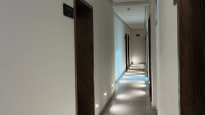Un pasillo largo y estrecho con paredes blancas y una puerta de madera a la izquierda.