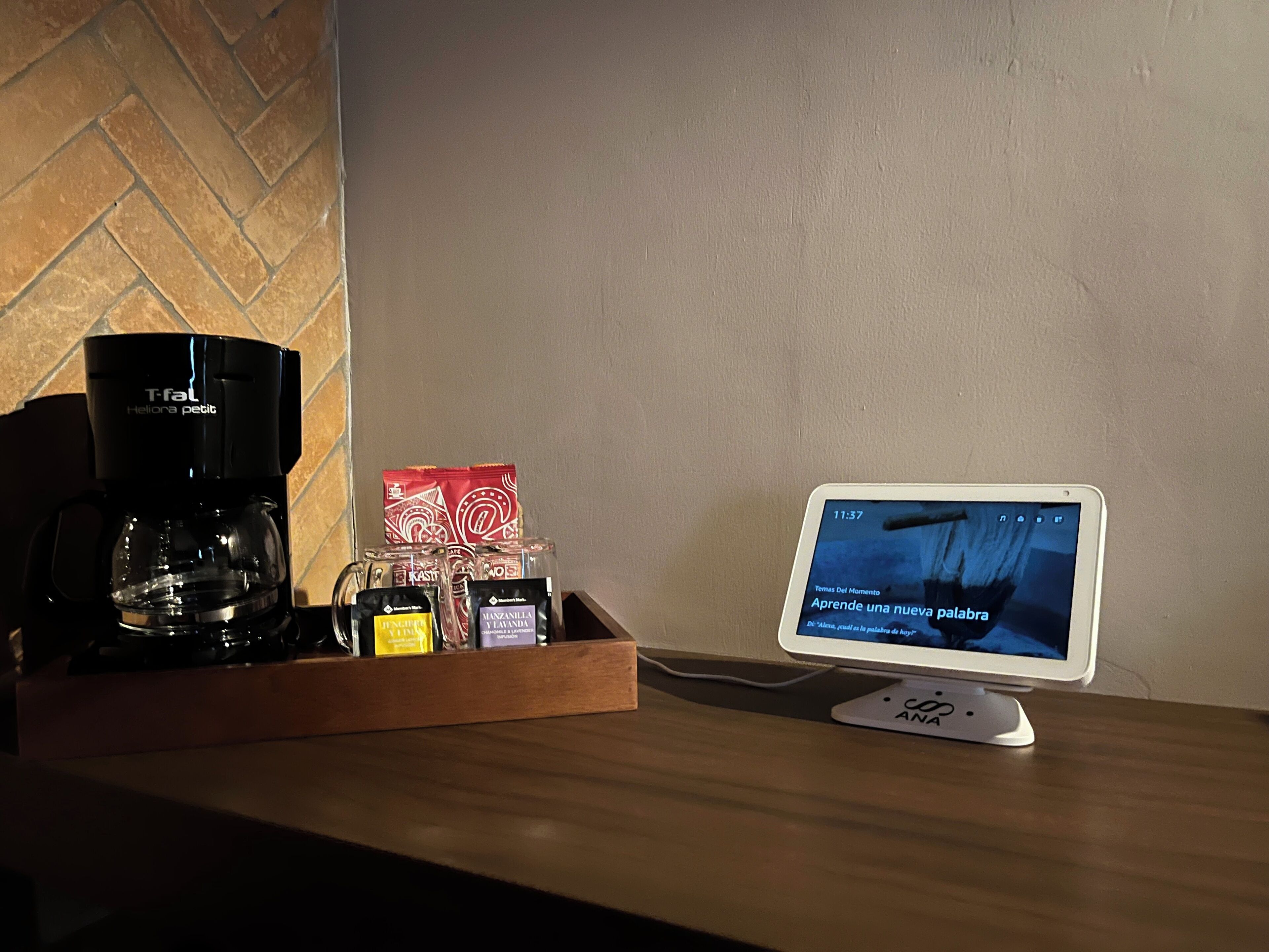 A coffee maker, a tray with coffee pods, and a tablet displaying a Spanish learning app.
