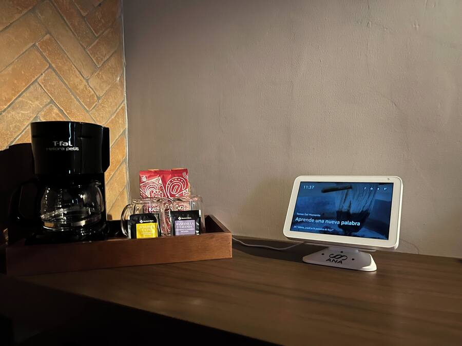 A coffee maker, a tray with coffee pods, and a tablet displaying a Spanish learning app.