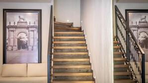 Una escalera con una estatua de león en la parte superior, un banco acolchado y un cuadro con una estatua similar.