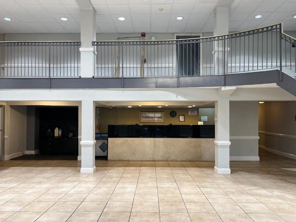 A spacious lobby with a reception desk, a second-floor balcony, and a tiled floor.