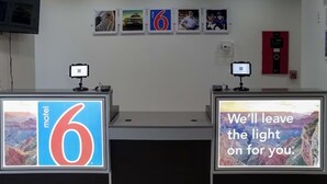 Ein Motel-Rezeptionsschalter mit zwei Monitoren, die das Logo des Motels und eine motivierende Botschaft zeigen.