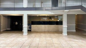 Eine großzügige Lobby mit Empfangsschalter, Säulen und einem Balkon mit Metallgeländern.