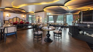 A modern hotel lobby with a round dining table, comfortable seating, and a view of the outdoors. - Lotus D'Orient Cruise (Tuan Chau)