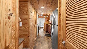 A narrow wooden hallway with a refrigerator on the right and a door at the end. - Cozy Tiny Cabin with a View!! (Decatur)