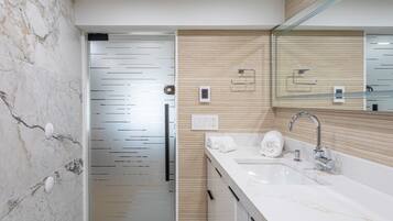 Une salle de bain moderne avec un mur en marbre, un mur recouvert de panneaux en bois, un lavabo avec un miroir et un porte-serviettes.