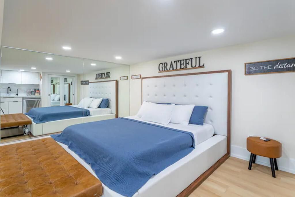 Ein Hotelzimmer mit einem großen Bett, einem kleinen Nachttisch, einem Spiegel und einer Wand mit motivierenden Zitaten.