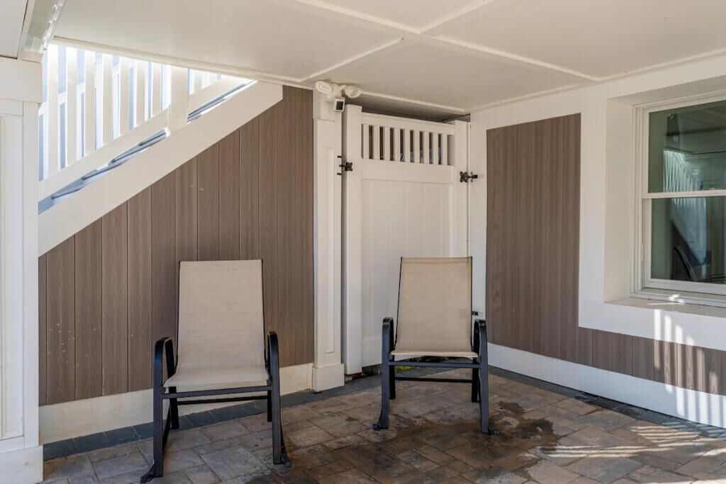 A corner of a room with two chairs, a white door, and a window.