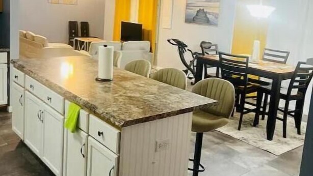 Une cuisine moderne dotée d’un plan de travail en marbre, de meubles blancs et d’un coin repas avec une table et des chaises.
