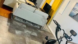Un espace de vie compact comprenant un canapé, une table à manger et un téléviseur. On y trouve également un vélo et une petite table avec une chaise.