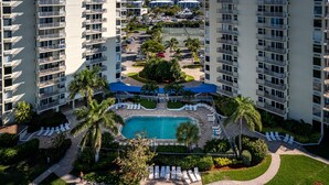 A high-rise hotel with a central swimming pool, multiple balconies, and a well-maintained garden area. - Estero Beach and Tennis (Fort Myers Beach)