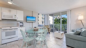 A modern kitchen with a dining area, a sofa, and a balcony with a view. - Estero Beach and Tennis (Fort Myers Beach)