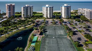 A high-rise hotel complex with multiple buildings, a parking lot, and a tennis court. - Estero Beach and Tennis (Fort Myers Beach)