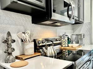 A modern kitchen with a stainless steel stove, a coffee machine, and a decorative tile backsplash.