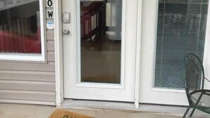 A house with a number '38' and the word 'ALLOW' on the door, a glass door, and a metal chair outside.