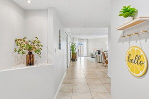 Um corredor com uma planta, uma placa com a palavra 'hello' e uma área de refeições ao fundo.