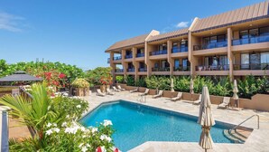 A hotel with a pool, lounge chairs, and a multi-story building with balconies. - Kona Pacific C618 Top fl Seaview With ac, Elevator (Kailua-Kona)