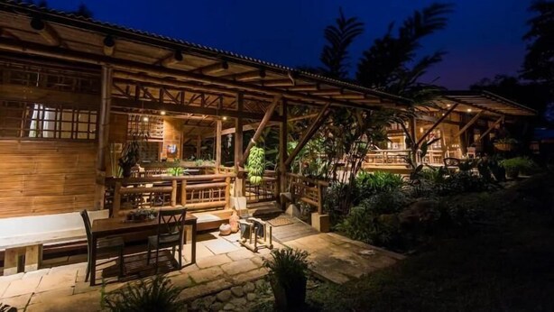 Ein Holzgebäude mit überdachter Terrasse, Steinböden und Sitzgelegenheiten im Freien.
