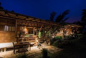 A wooden building with a covered patio area, stone flooring, and outdoor seating. - Casa Solaz Waterfall Lodge for 8 | Finca Anjalá (1 KM Sur Este Platanares Perez Zeledón)