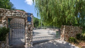 A stone gate with a metal fence, a sign with stars, and a tree in the background. - Villa Brkic with private pool and playground- ideal for families & friends (Dicmo Osoje)