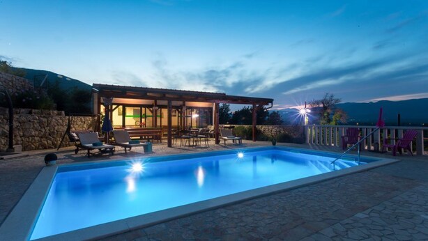 A swimming pool with lounge chairs and a covered seating area, surrounded by stone walls and a view of the mountains. - Villa Brkic with private pool and playground- ideal for families & friends (Dicmo Osoje)