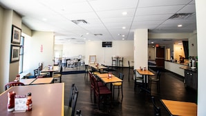 A spacious restaurant with multiple tables and chairs, a kitchen area, and a clean, well-lit interior. - Rochester Hotel (Rochester)