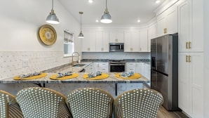 A modern kitchen with white cabinets, stainless steel appliances, and a central island with seating.