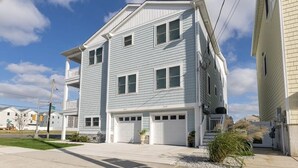 A two-story residential building with a light blue exterior, white trim, and a front porch.