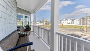 A covered porch with wicker furniture and a view of a street with houses and traffic lights.
