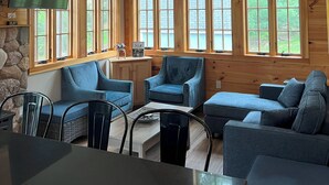 Ein gemütliches Blockhäuschen-Interieur mit Essbereich, Sitzgelegenheiten und großen Fenstern.