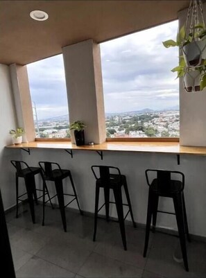 Enjoy a panoramic city view from the bar area with a large window, a sleek counter, and comfortable bar stools.