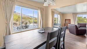 A dining area with a wooden table, chairs, and a view of a desert landscape through large windows. - NW Tucson family friendly house with Catalina mountain views (Tucson)