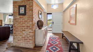 A living room with a brick wall, a large vase, a bench, and a patterned rug. - NW Tucson family friendly house with Catalina mountain views (Tucson)