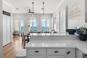 A modern kitchen with a large island, pendant lighting, and a view of the ocean through the windows. - BellaVista on the Beach*HotTub*Gulf Front*3 Patios (Miramar Beach)