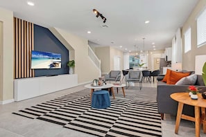Uma sala de estar moderna com televisão, sofás, mesa de centro e tapete listrado.